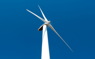 Een foto van een windmolen, met een blauwe lucht op de achtergrond
